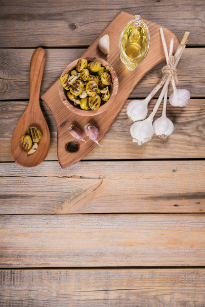 Grilled olives with garlic, olive oil and spices on wooden backg - Fotoğraf, Görsel
