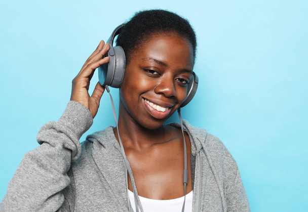 Портрет красивой молодой африканской женщины, улыбающейся и слушающей музыку
 - Фото, изображение