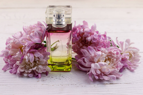 Perfume de mujer con flores sobre fondo blanco de madera
 - Foto, Imagen