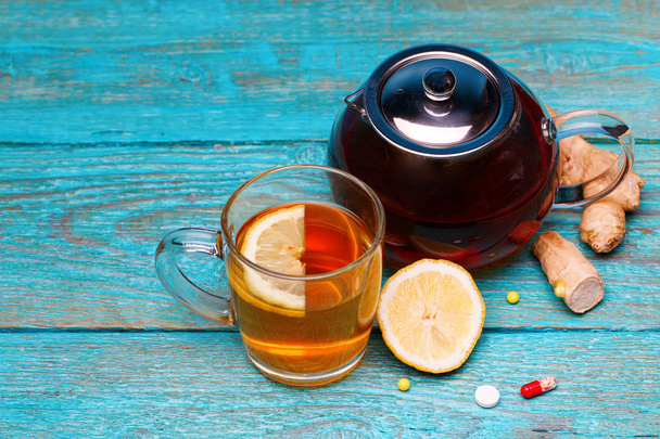 Κρύα φάρμακα, τσάι, λεμόνι και τζίντζερ σε ξύλινο μπλε φόντο - Φωτογραφία, εικόνα