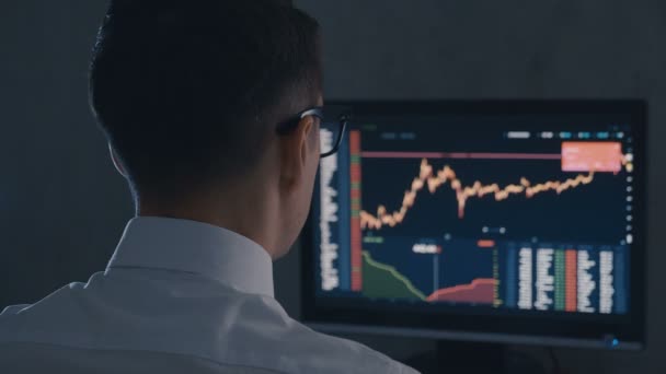 Obchodník s bílou košilí a sklenicemi analyzuje prodejní trh. Pohled na Stockbroker pracuje s finančním trhem v noční kanceláři. - Záběry, video