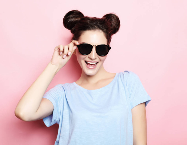 Positive funny brunette girl with hairbuns wearing sunglasses - Zdjęcie, obraz