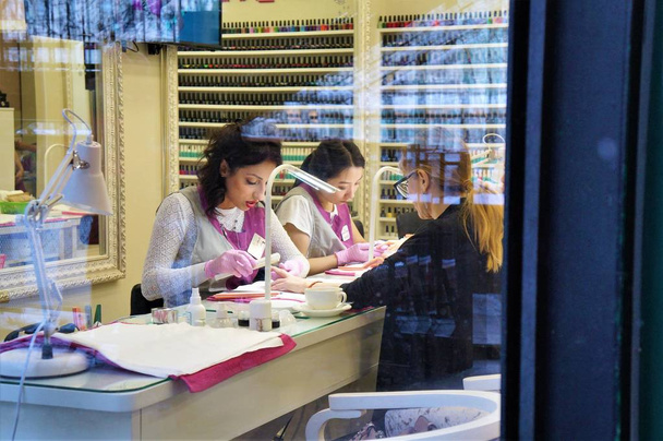 12.18.2018 Russia. Moscow.  Nail master makes a manicure client. view through the glass. - Fotó, kép