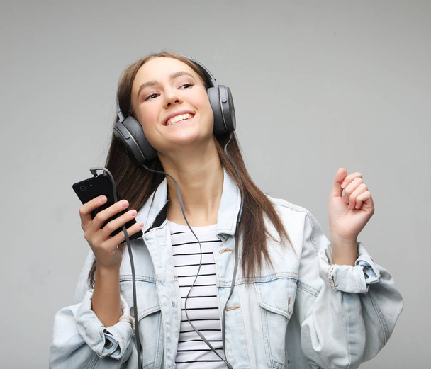 Beautiful young woman listening to music in headphones with smartphone  - Foto, Imagen
