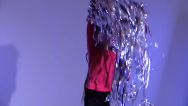 Slow motion of girl throwing up tinsel on gray background. - Footage, Video