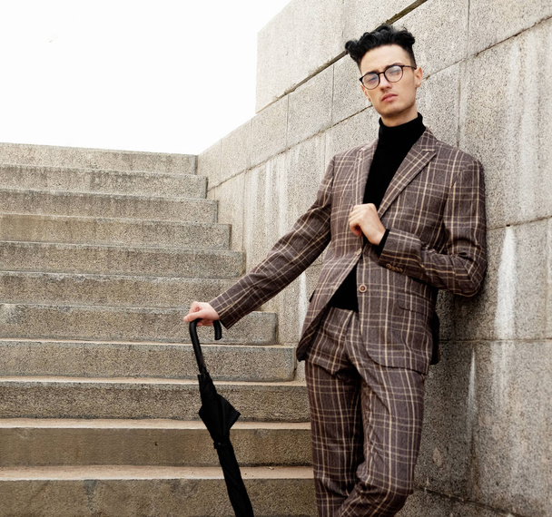 fashionable young man in glasses with umbrella standing on the stairs - Fotografie, Obrázek