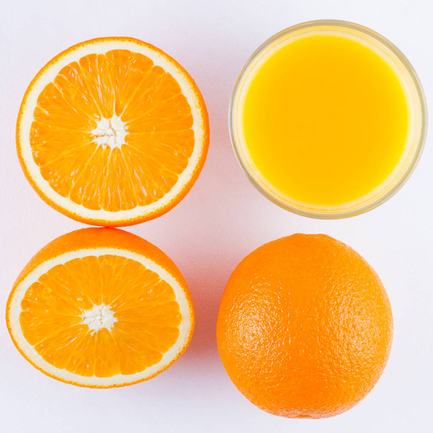 Orange fruits with juice, concept. Orange juice and halves of oranges on white background. Citrus for making juice. Whole and squeezed oranges and glass of juice - Foto, Imagem
