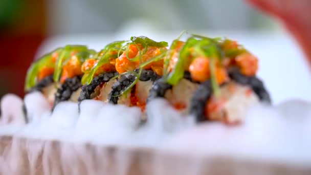 Mano con palillos tomando sushi servido en humo en el restaurante japonés
. - Imágenes, Vídeo