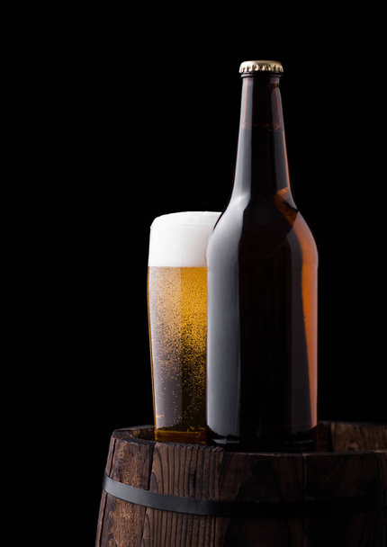 Cold bottle and glass of craft beer on old barrel - Photo, Image