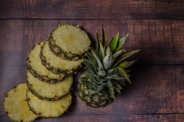 sliced pineapple on a dark board background.  Fruit on the kitchen table. - Photo, image