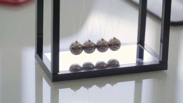 テーブルの上に黒いフレームで揺れる金属球を示すニュートンクレードルオフィス玩具 - 映像、動画