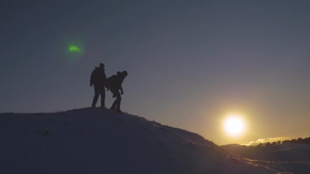 Travelers descend from the tops of the hill. tourists go down the snowy mountain at sunset. Alpenists travel, hiking. teamwork traveler. - Footage, Video