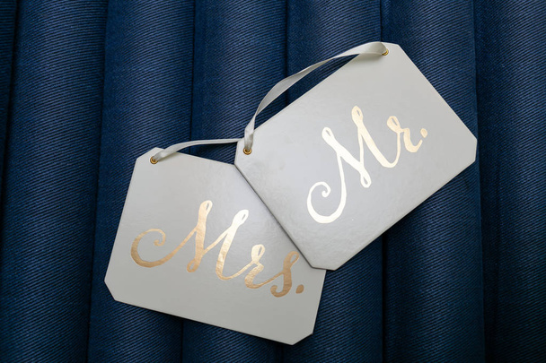 Witte vierkante plaques met witte linten en gouden opschriften de heer en mevrouw geïsoleerd op blauwe achtergrond. - Foto, afbeelding