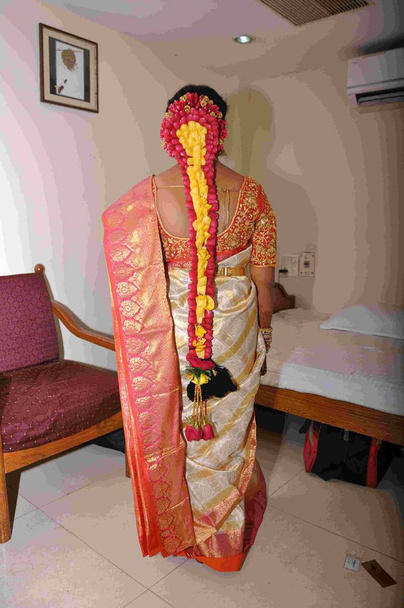 hindu menyasszony mutatja vissza a hosszú haja díszített rózsaszirom a vörös és sárga - Fotó, kép