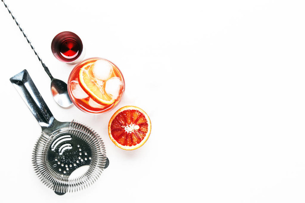 Trendy alcoholic cocktail Negroni with dry gin, red vermouth and red bitter, orange slice and ice cubes. White background, bar tools, top view, copy space - Fotoğraf, Görsel