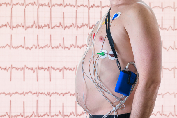 Um homem é submetido a um exame cardíaco no fundo de uma tela vermelha com um cardiograma. O método do halter
. - Foto, Imagem