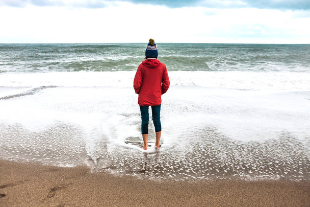 Paljain jaloin nainen katsoo talven meri
. - Valokuva, kuva