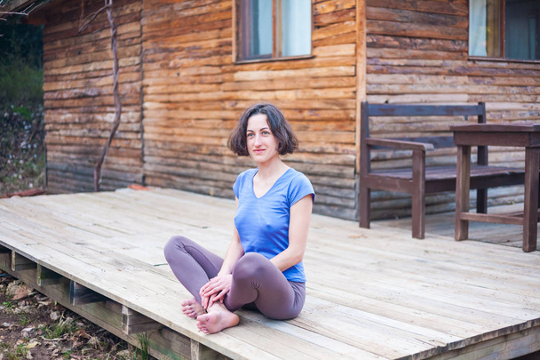 A woman is sitting on the porch of an old wooden house. - Foto, afbeelding