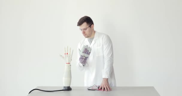 科学者のエンジニアは、センサーと手袋で彼の手の動きを繰り返すロボット補綴の手をテストしています. - 映像、動画