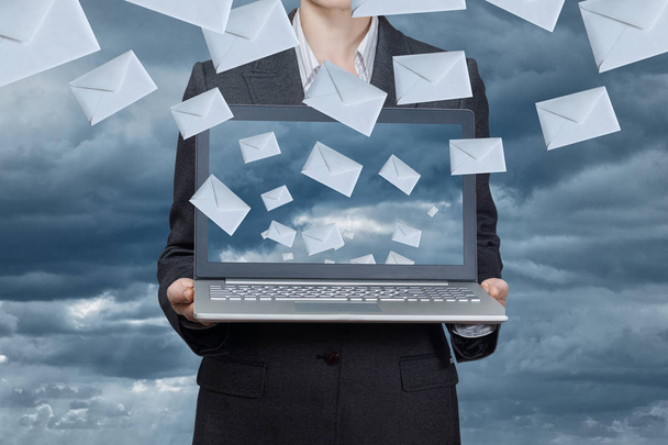 Een zakenvrouw houdt een notebook met envelop iconen vliegen. - Foto, afbeelding