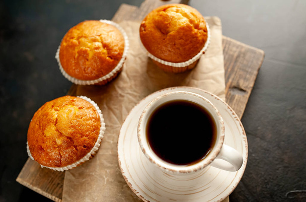 frisch gebackene Muffins serviert mit einer Tasse Kaffee auf Holzbrett - Foto, Bild