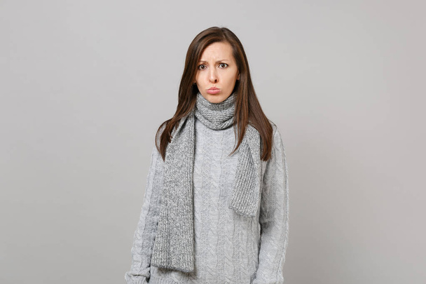 Προσβεβλημένη νεαρή γυναίκα με γκρι πουλόβερ, μαντήλι κατσουφιασμένη χείλη απομονώνονται - Φωτογραφία, εικόνα
