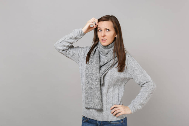 Pensive femme concernée en écharpe pull gris regardant vers le haut tenant
 - Photo, image