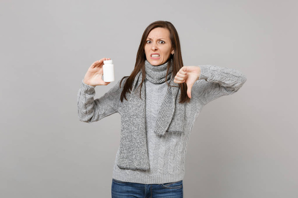 Mujer irritada en suéter gris, bufanda que muestra el pulgar hacia abajo mantenga m
 - Foto, Imagen