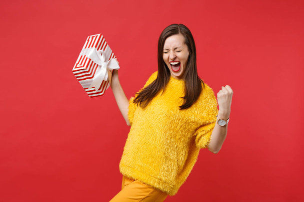 Happy young woman screaming, doing winner gesture, holding red s - Foto, afbeelding