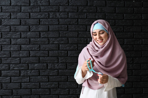 Moslimvrouw met Tasbih op donkere achtergrond - Foto, afbeelding