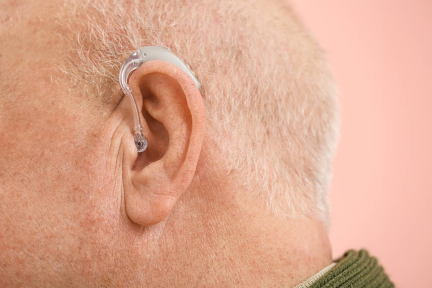 Senior man with hearing aid on color background, closeup - Фото, изображение