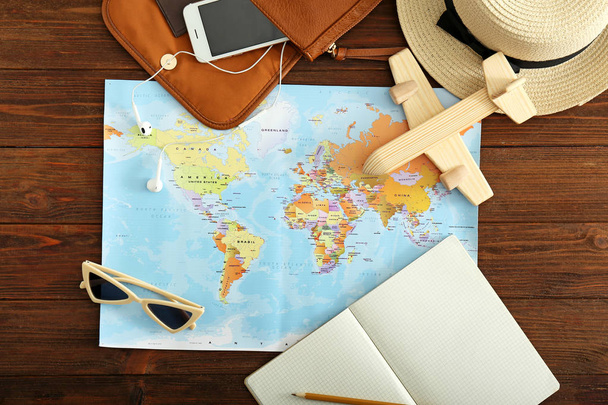 Carte du monde avec avion, téléphone portable et accessoires féminins sur table en bois. Concept de voyage
 - Photo, image
