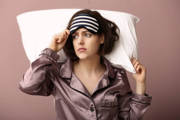 Mujer estresada con máscara y almohada sobre fondo de color
 - Foto, Imagen