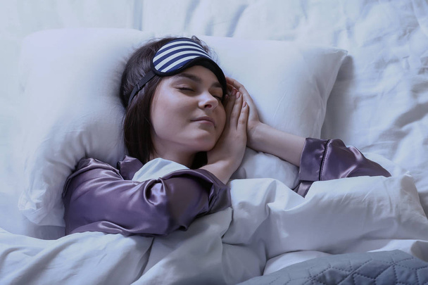 Jeune femme avec masque de sommeil au lit la nuit
 - Photo, image