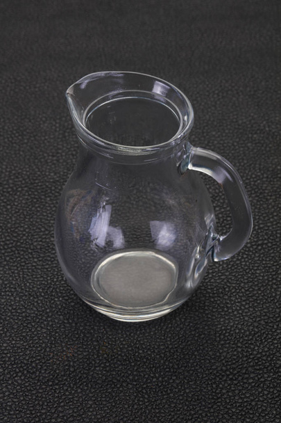 Empty glass jug over black background - Foto, Bild
