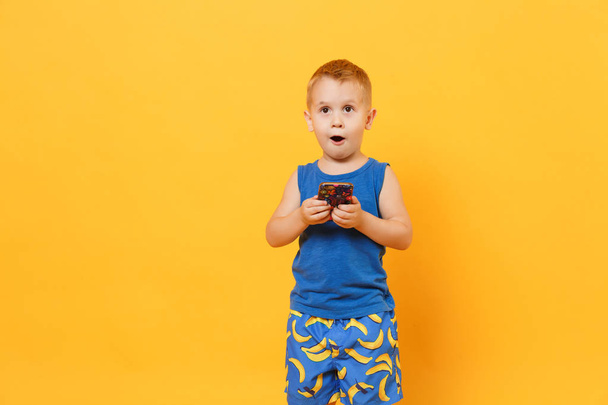 Kid boy 3-4 anos de idade em roupas azuis segurar celular isolado em
 - Foto, Imagem