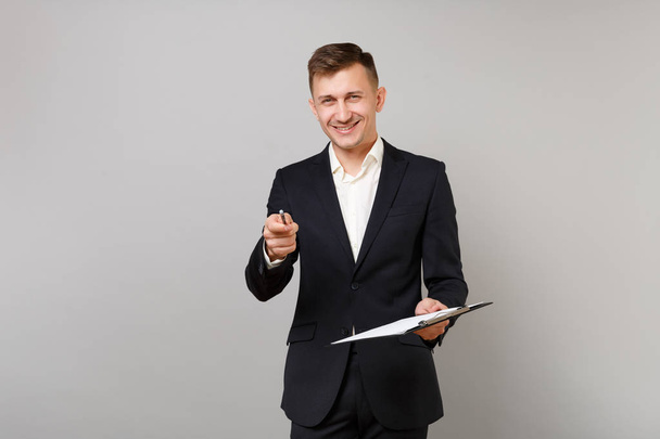 Lächelnder junger Geschäftsmann im klassischen Anzug zeigt mit Bleistift auf ca. - Foto, Bild