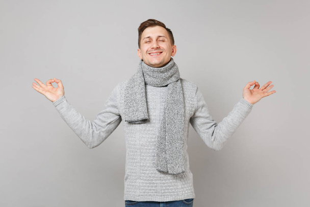 Молодой человек в сером свитере, шарф с закрытыми глазами, держащийся за руки
  - Фото, изображение