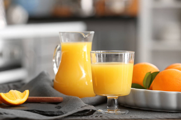 Lasi ja kannu tuoretta appelsiinimehua pöydällä
 - Valokuva, kuva