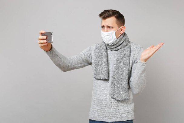 Concerned young man in gray sweater, scarf with sterile face mas - Foto, Imagem