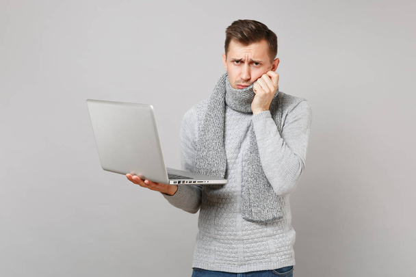 Sconvolto giovane uomo in maglione, sciarpa di lavoro sul computer portatile pc
, - Foto, immagini