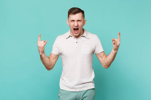 Кричущий молодий чоловік у повсякденному одязі, що зображує роги вгору жестом
 - Фото, зображення