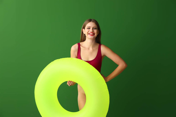 Hermosa mujer joven con anillo inflable sobre fondo de color - Foto, Imagen