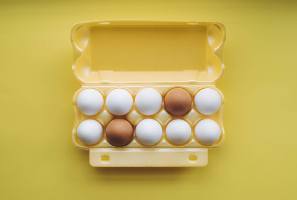 Eggs in carton on the yellow background. - Valokuva, kuva