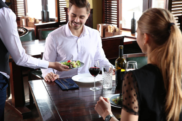 Waiter serving guests in restaurant - Foto, afbeelding