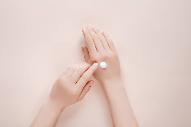 Woman moisturizing her hand with cosmetic cream lotion with copy space on beige background. Concept template feminine blog, beauty concept - Fotografie, Obrázek