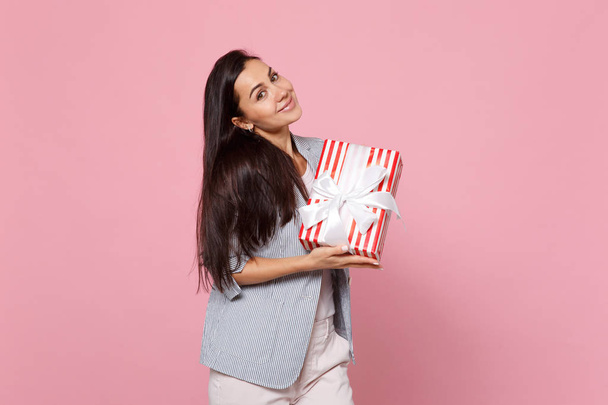 Гарненька молода жінка тримає червону смугасту подарункову коробку з подарунковим ребрами
 - Фото, зображення