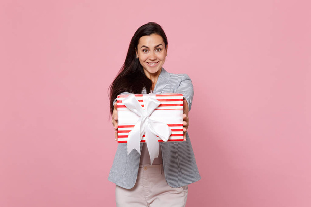 Χαρούμενη νεαρή γυναίκα κρατώντας κόκκινο ριγέ παρόν κουτί με πλευρά δώρο - Φωτογραφία, εικόνα
