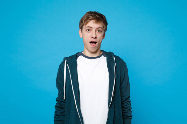 Portrait of surprised young man in casual clothes keeping mouth  - Foto, imagen