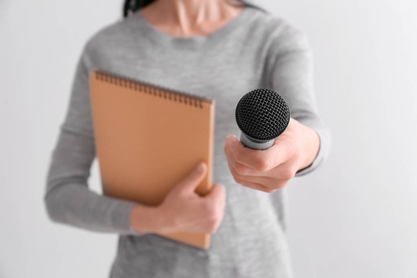 Periodista femenina con micrófono sobre fondo claro, primer plano
 - Foto, Imagen